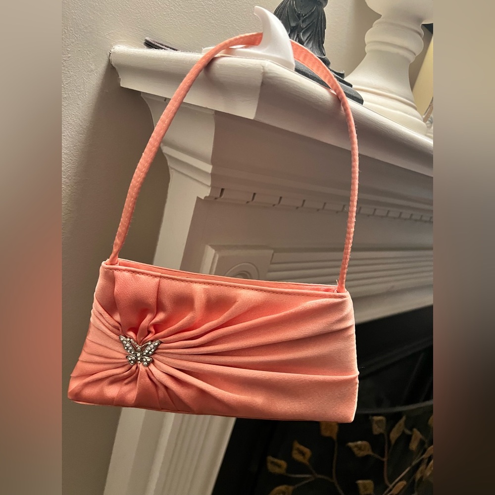 Small peach purse with silver butterfly emblem.
